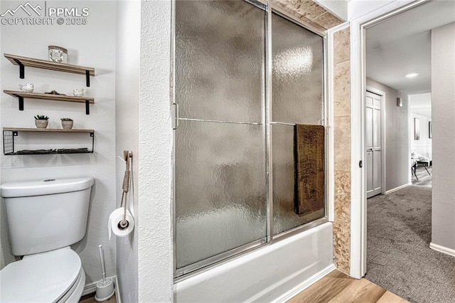 bathroom featuring hardwood / wood-style floors, toilet, and enclosed tub / shower combo