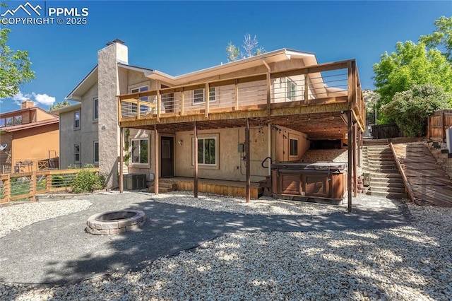 view of front of home with a hot tub, an outdoor fire pit, a deck, and central air condition unit