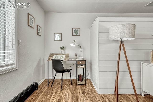 office area featuring wood-type flooring and a baseboard heating unit