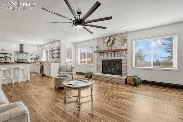 living room with a fireplace, light hardwood / wood-style floors, plenty of natural light, and ceiling fan