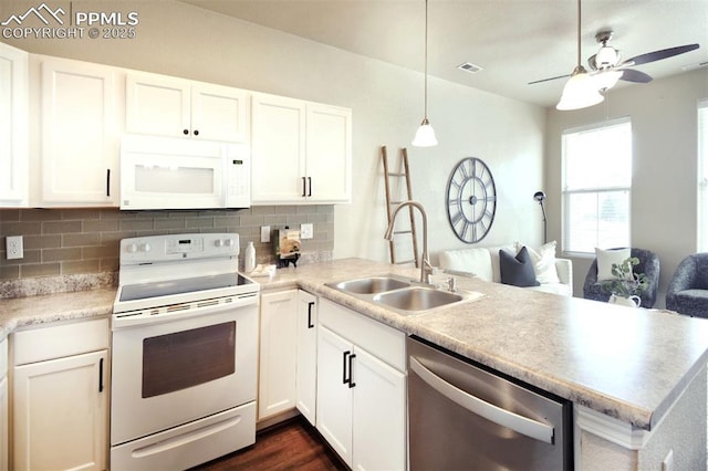 kitchen with white appliances, sink, hanging light fixtures, white cabinetry, and kitchen peninsula