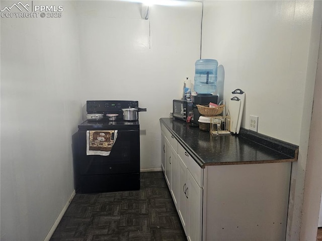 kitchen featuring black range with electric stovetop, dark parquet flooring, and white cabinets