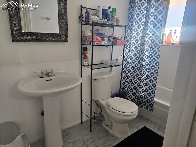 bathroom featuring shower / bathtub combination with curtain and toilet