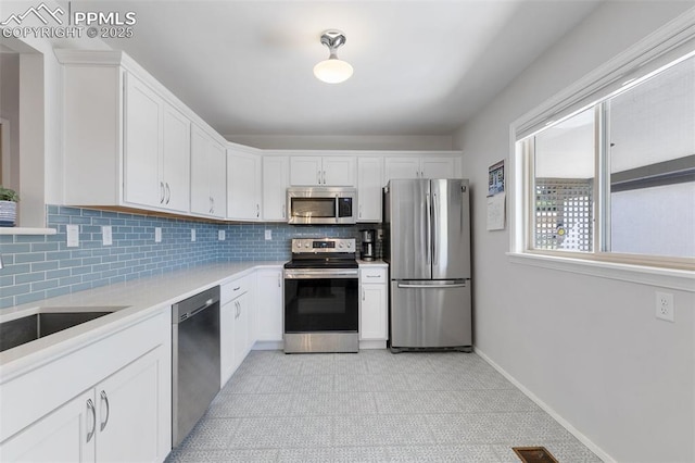 kitchen featuring backsplash, white cabinetry, sink, and stainless steel appliances