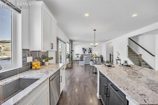 kitchen with white cabinetry, light stone countertops, stainless steel dishwasher, and decorative light fixtures