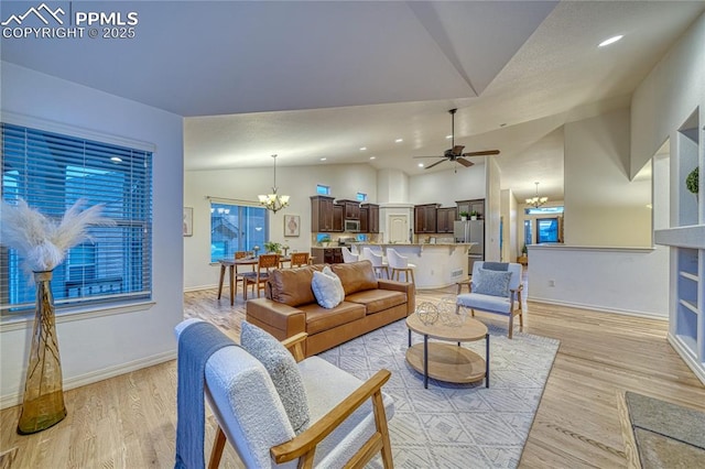 living room with light hardwood / wood-style flooring, ceiling fan with notable chandelier, and lofted ceiling