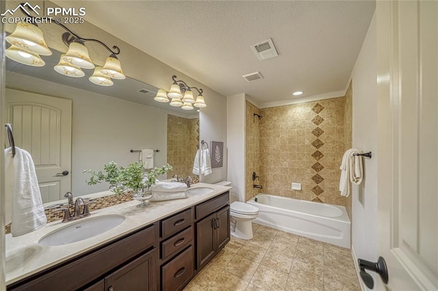 full bathroom with a textured ceiling, vanity, toilet, and tiled shower / bath