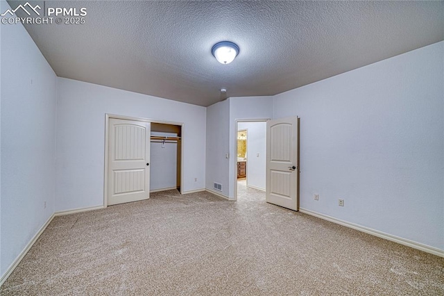 unfurnished bedroom with carpet flooring, a textured ceiling, and a closet