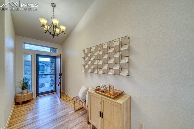 entryway with lofted ceiling, light hardwood / wood-style flooring, and a chandelier