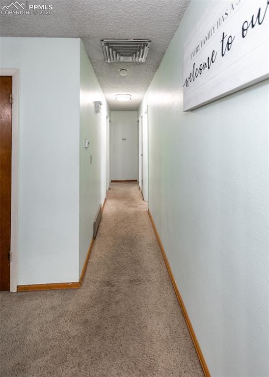 corridor with carpet floors and a textured ceiling