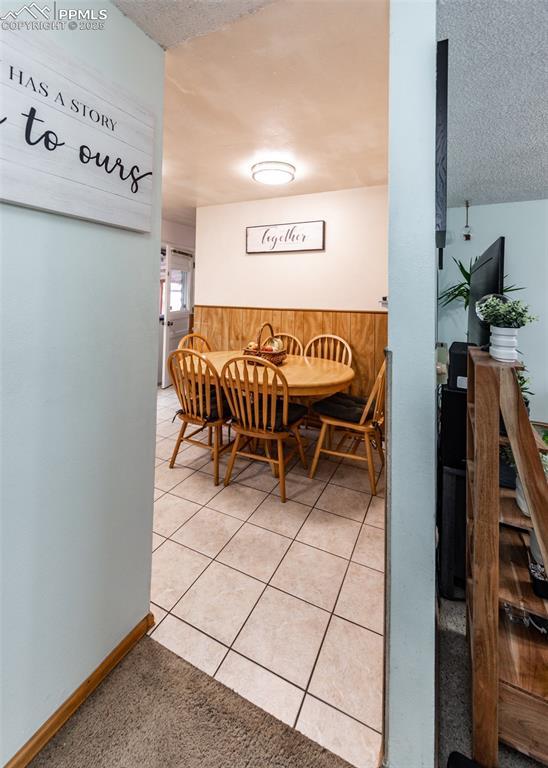 tiled dining space with a textured ceiling and wood walls