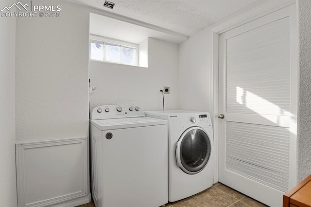 washroom with light tile patterned floors, a textured ceiling, and separate washer and dryer