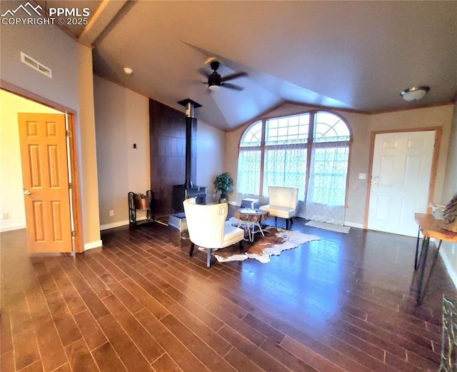 interior space featuring lofted ceiling, ceiling fan, dark hardwood / wood-style flooring, and a wood stove