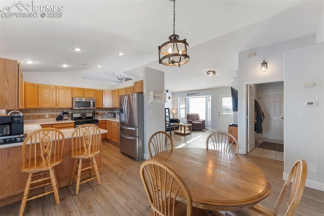 dining space featuring a notable chandelier, sink, vaulted ceiling, and light wood-type flooring