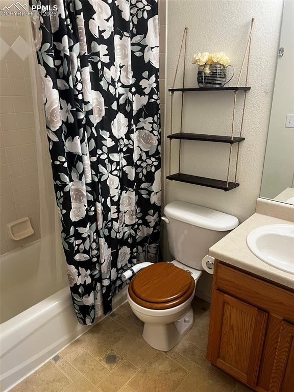 full bathroom with vanity, shower / bath combination with curtain, and toilet