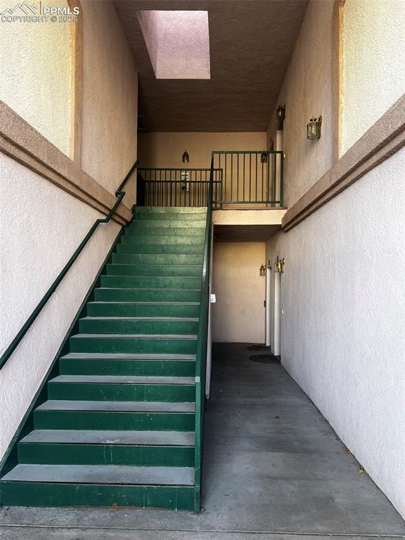 stairs featuring concrete floors and a skylight