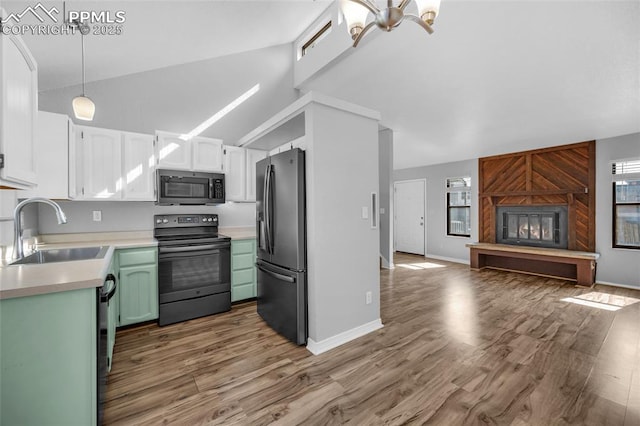 kitchen with lofted ceiling, sink, electric range, stainless steel fridge, and a large fireplace