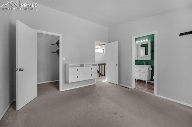 unfurnished bedroom featuring ensuite bath, a spacious closet, sink, and carpet floors