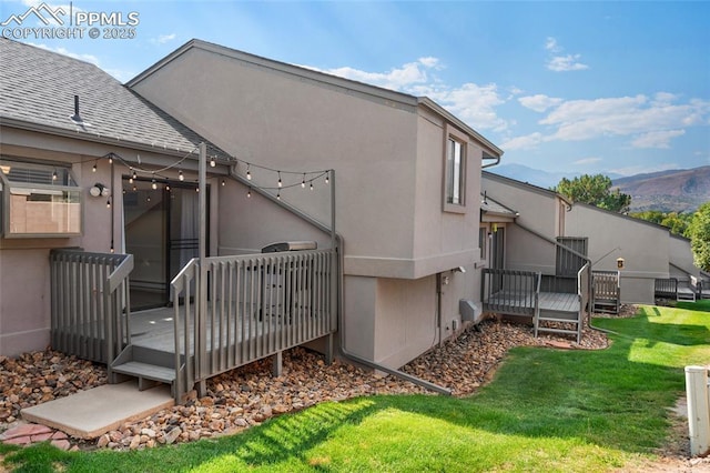 back of house with a deck with mountain view and a yard