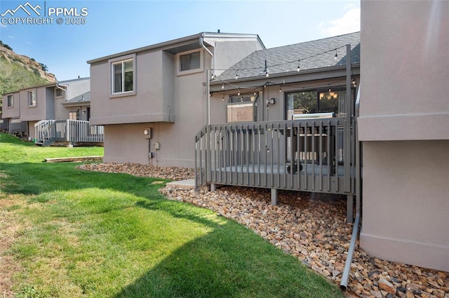 rear view of property featuring a lawn and a deck