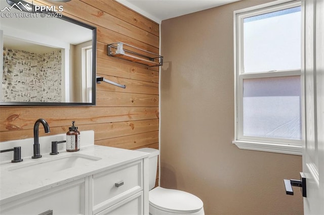 bathroom with vanity, wood walls, and toilet