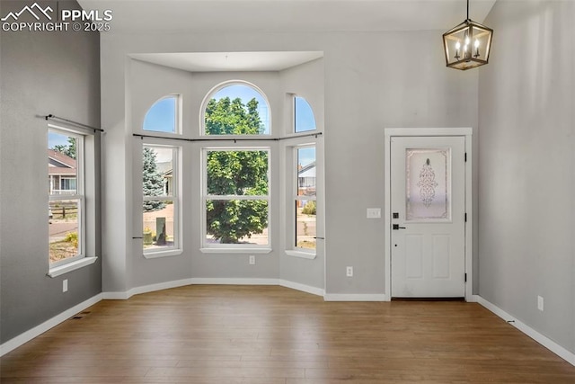 foyer with a towering ceiling, hardwood / wood-style flooring, and an inviting chandelier