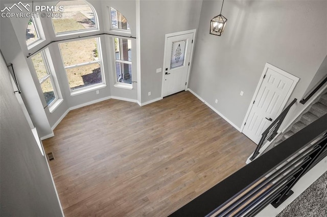 foyer featuring a high ceiling, hardwood / wood-style flooring, plenty of natural light, and a notable chandelier