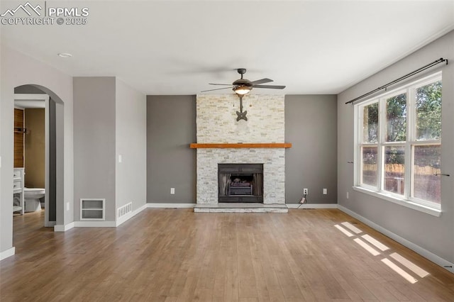 unfurnished living room with ceiling fan, a fireplace, and wood-type flooring