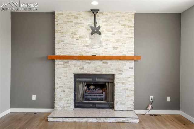 details with hardwood / wood-style flooring and a stone fireplace