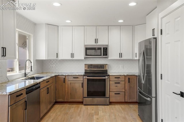 kitchen featuring white cabinets, light stone counters, sink, and appliances with stainless steel finishes