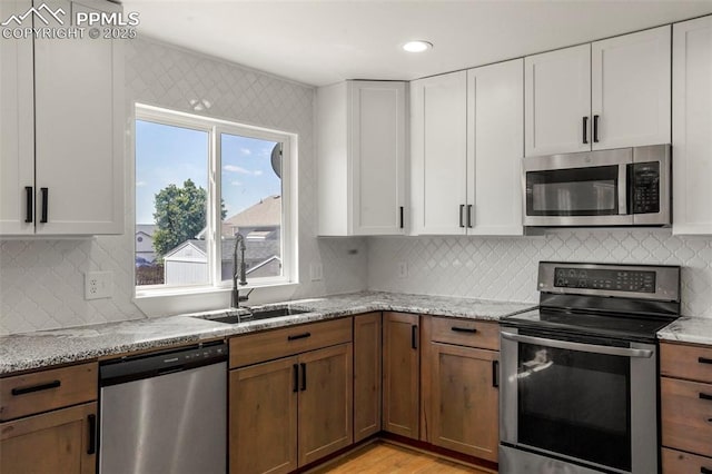 kitchen with light stone counters, sink, white cabinets, and appliances with stainless steel finishes