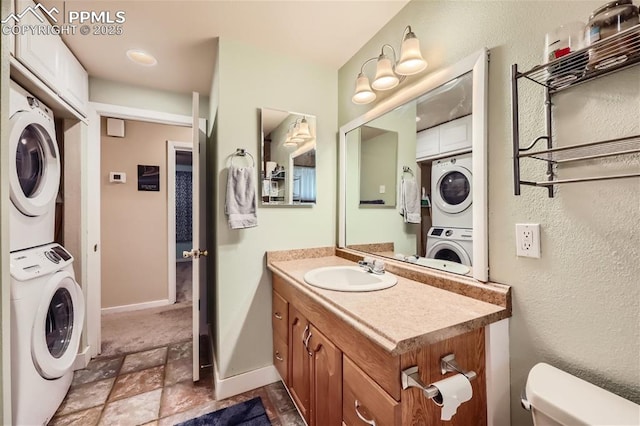 bathroom with vanity, stacked washer / drying machine, and toilet