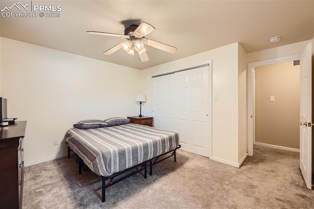 bedroom with ceiling fan, light carpet, and a closet