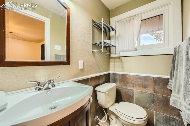 bathroom with vanity, toilet, and tile walls