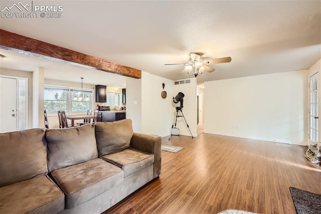 living room featuring beam ceiling, ceiling fan, and hardwood / wood-style floors