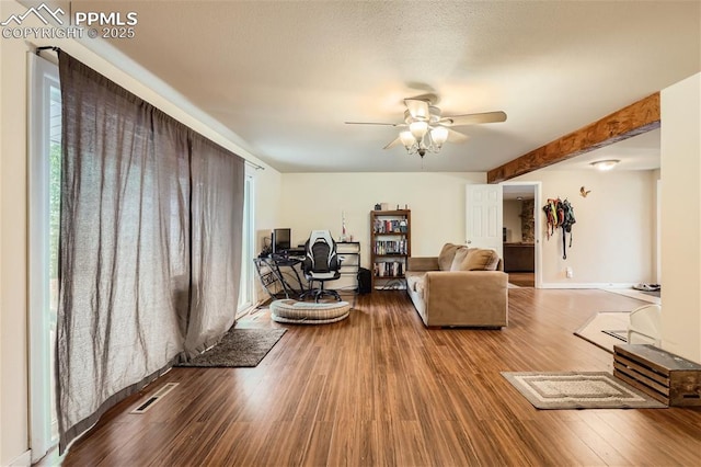 living room with beamed ceiling, hardwood / wood-style floors, a wealth of natural light, and ceiling fan