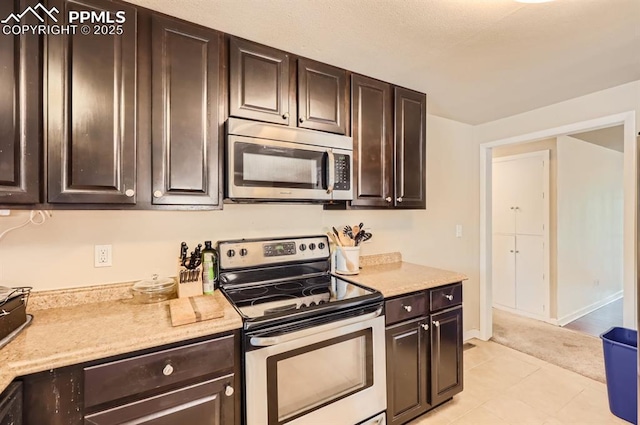 kitchen with appliances with stainless steel finishes, light tile patterned floors, and dark brown cabinets