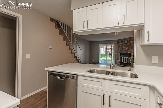 kitchen with a fireplace, dishwasher, white cabinets, and sink