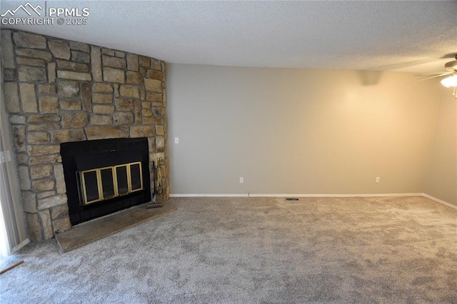 unfurnished living room with a textured ceiling, carpet floors, a stone fireplace, and ceiling fan