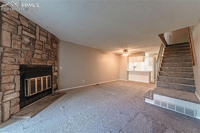 unfurnished living room featuring a fireplace, a textured ceiling, ceiling fan, and carpet flooring