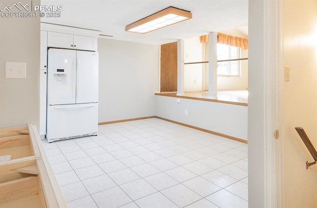 kitchen with light tile patterned floors, white cabinets, and white refrigerator with ice dispenser