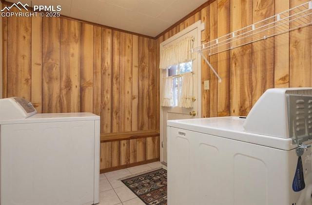 washroom with wood walls, washer and clothes dryer, and light tile patterned floors