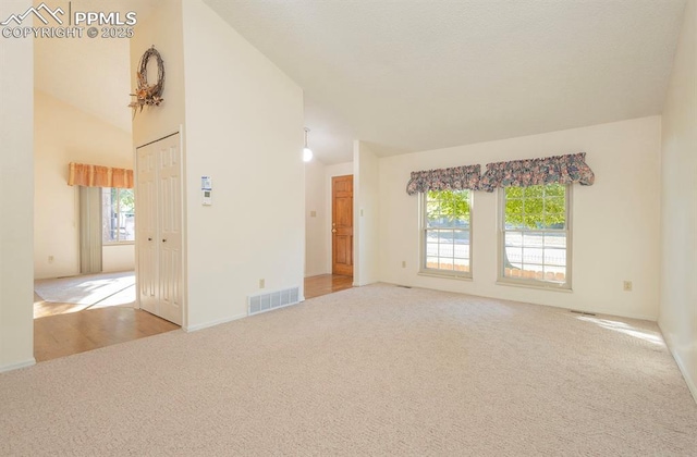 carpeted spare room with lofted ceiling