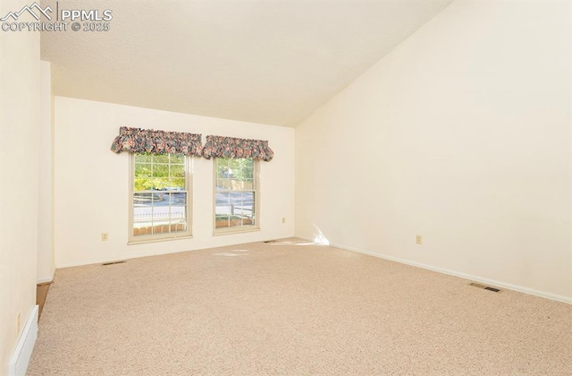 carpeted empty room with vaulted ceiling