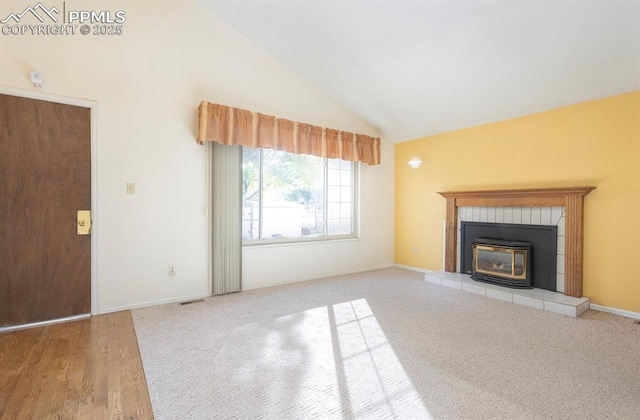 unfurnished living room with carpet, high vaulted ceiling, and a tiled fireplace