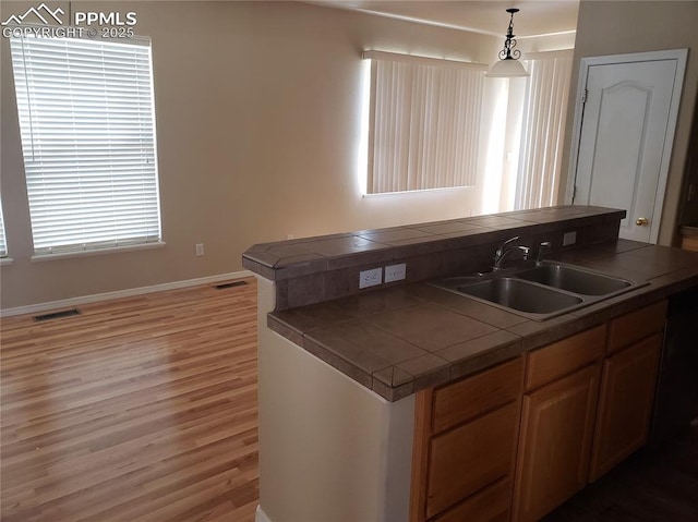 kitchen featuring tile counters, sink, hanging light fixtures, and dark wood-type flooring