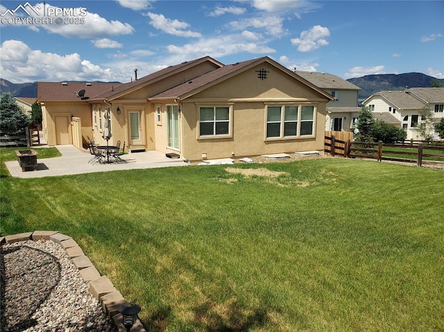 back of property featuring a patio area, a mountain view, and a yard