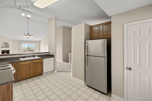 kitchen with sink, an inviting chandelier, stainless steel fridge, white dishwasher, and pendant lighting