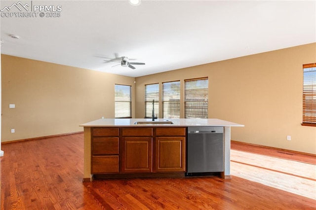 kitchen with a kitchen island with sink, sink, stainless steel dishwasher, ceiling fan, and dark hardwood / wood-style flooring