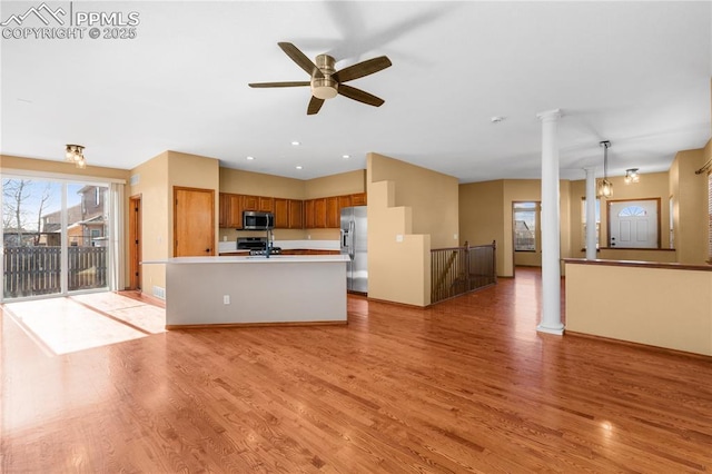 kitchen featuring pendant lighting, light wood-type flooring, stainless steel appliances, and a kitchen island with sink